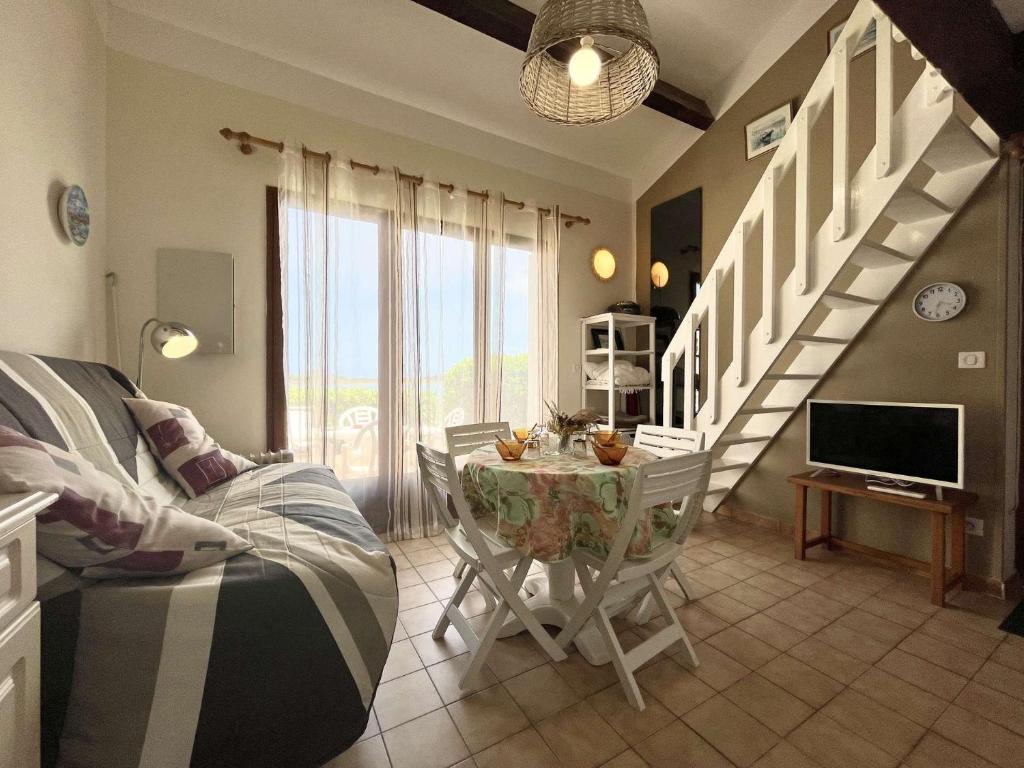 un salon avec une table et des chaises et un escalier dans l'établissement Maison Studio mezzaninne - Gruissan Ayguades AY090-022, à Vires
