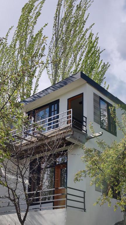 a white house with a balcony and a tree at Sanctuary Resort Hunza in Hunza Valley