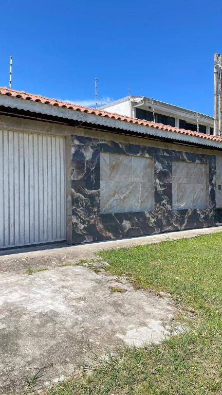 a building with a stone wall next to a yard at Casa Peruíbe Somar in Peruíbe