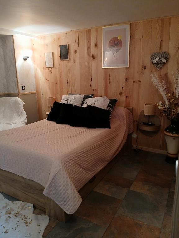 - une chambre avec un grand lit et des murs en bois dans l'établissement Les quatres saisons de isa, à Dole