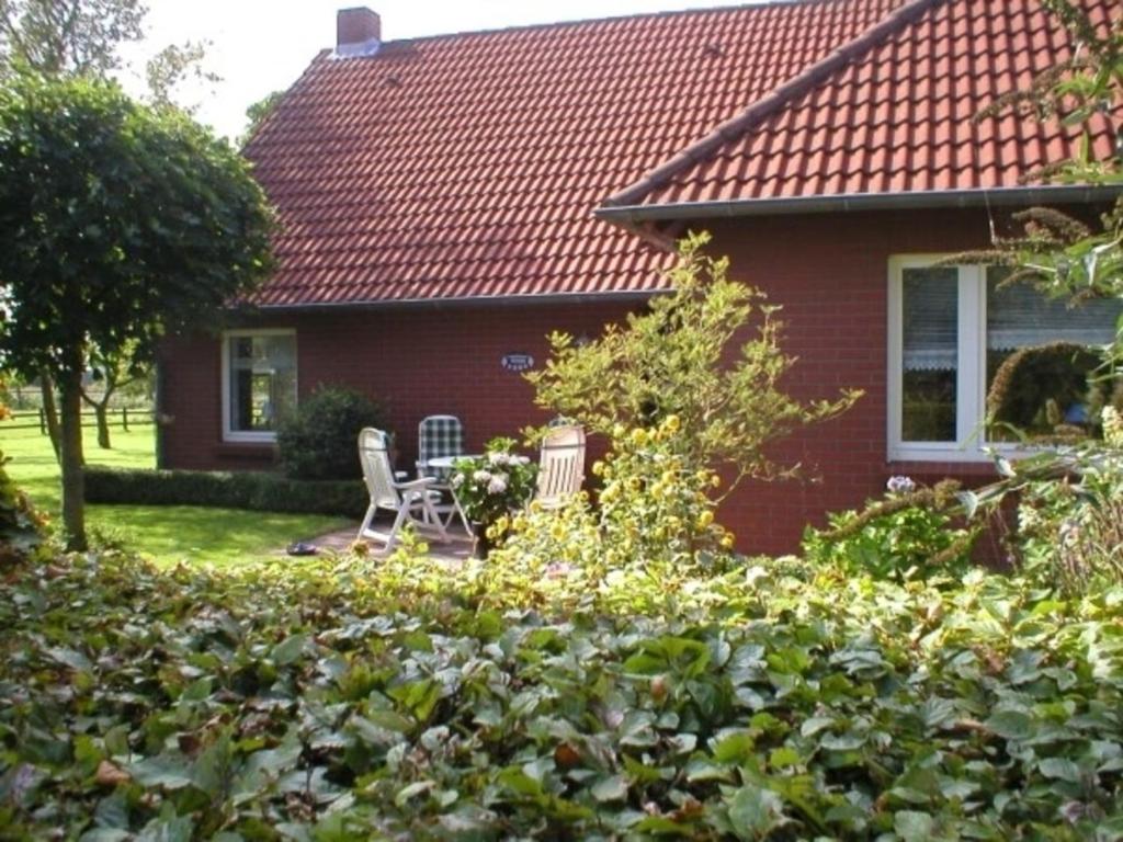 a red house with two chairs in the yard at Landhaus am Kleeweg in Osteel