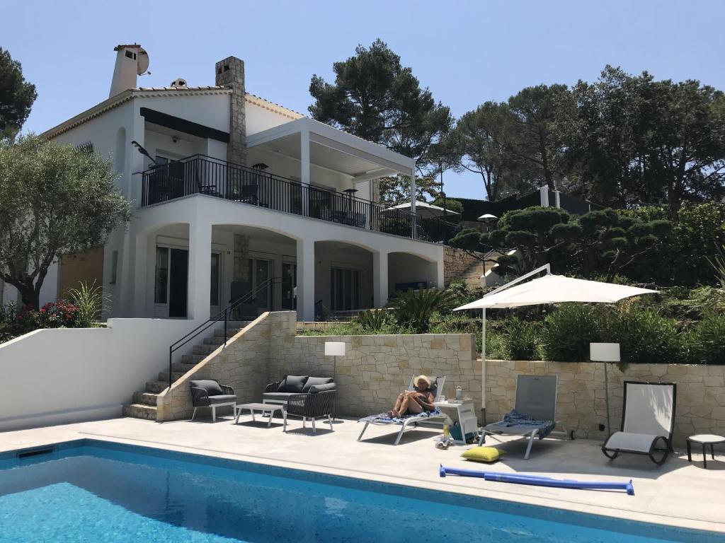 une femme assise dans une chaise à côté d'une maison dans l'établissement Villa avec piscine à 5 min du Golf et 15 min des plages, à Biot