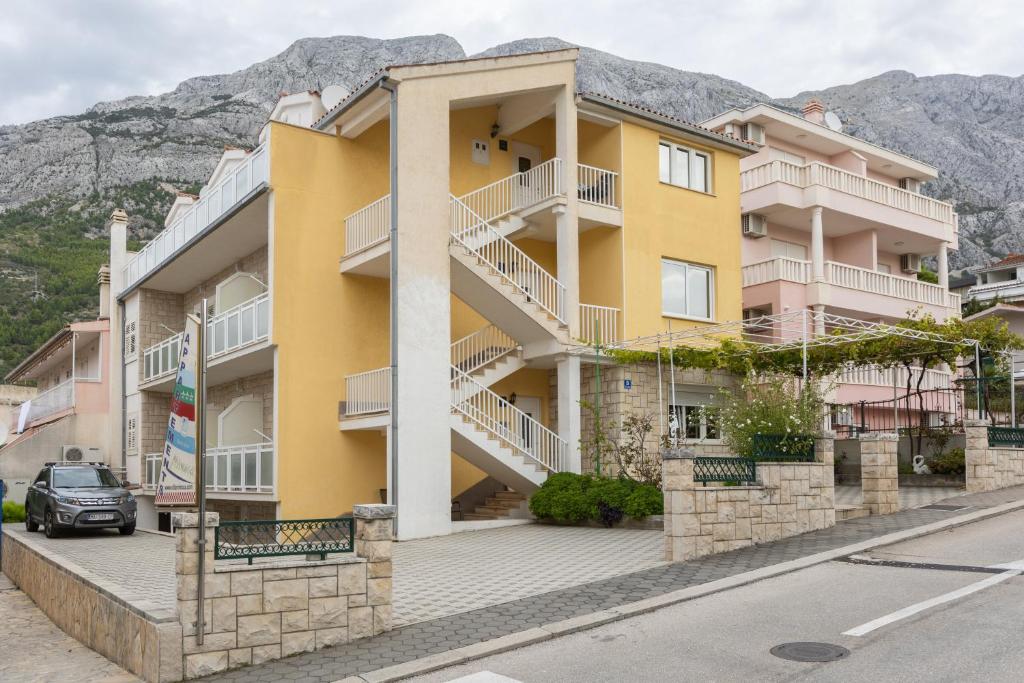 a yellow building with white balconies on a street at Villa Mimoza in Baška Voda