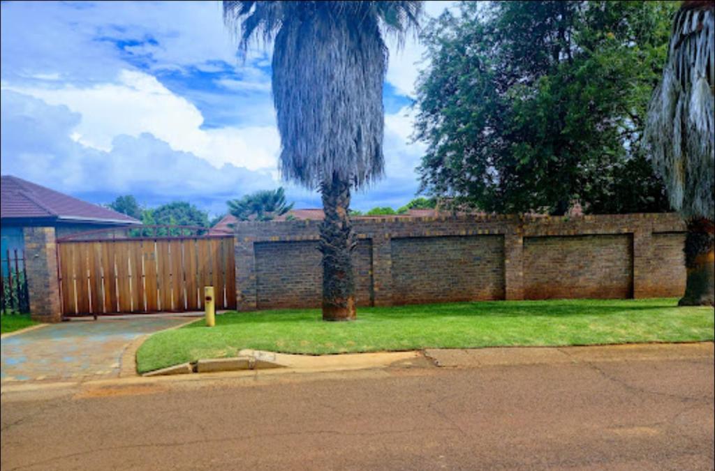 a palm tree in a yard next to a fence at Den-Away Guesthouse Self Catering Middelburg Mpumalanga in Mhluzi