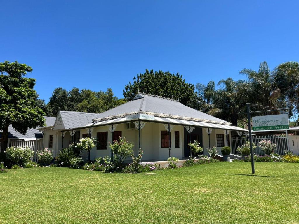 an old building with a roof on a lawn at Wooden Door Guesthouse in Brits
