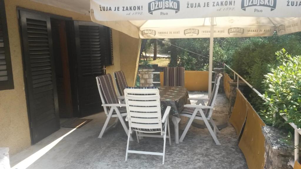 een tafel en stoelen onder een parasol op een patio bij Apartment Ivan in Cres