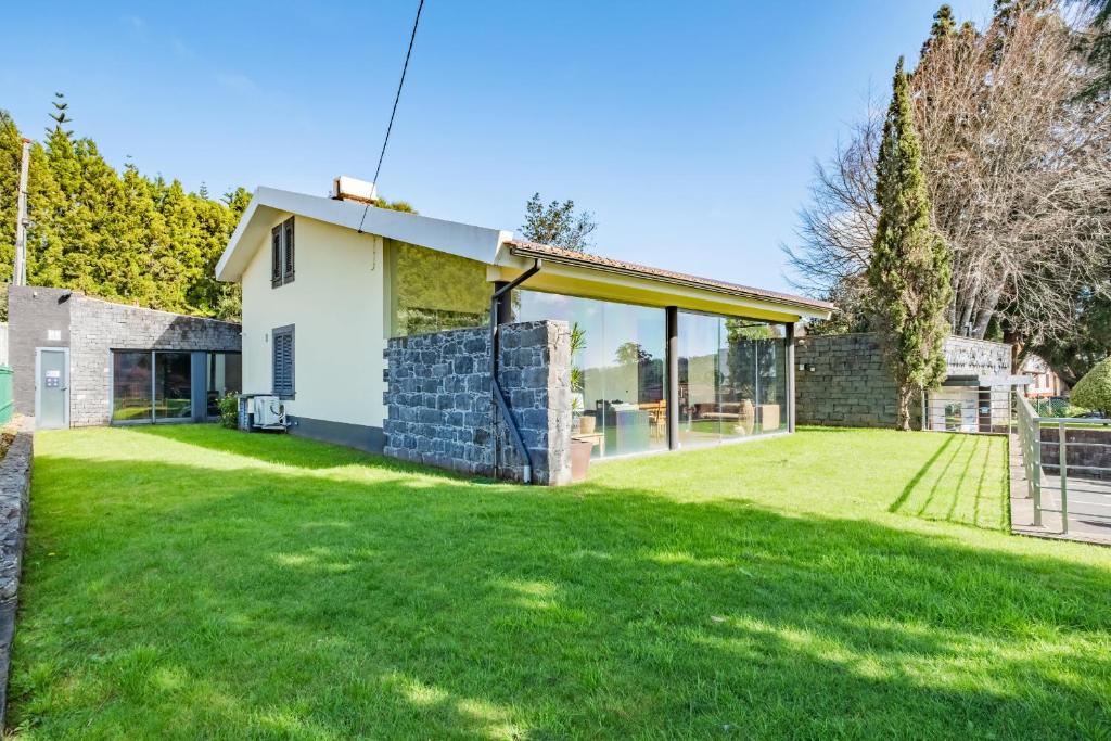 dom z dużym dziedzińcem z zieloną trawą w obiekcie Casa do Santo by Homie w mieście Santo António da Serra