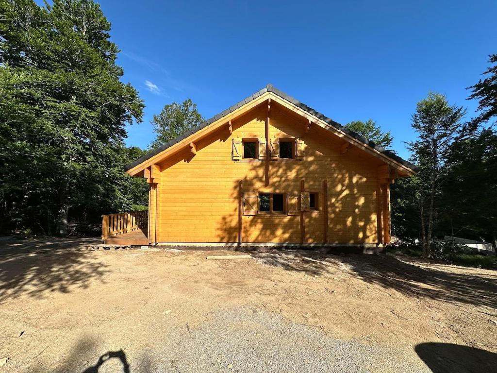 une petite maison en bois avec une grande cour dans l'établissement Chalet en fôret - 15 personnes, à Dourbies