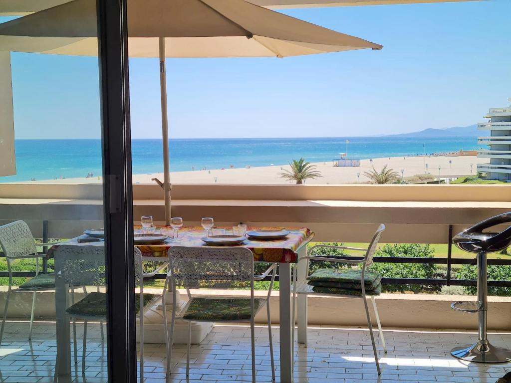 - une table et des chaises avec un parasol et la plage dans l'établissement T3 climatisé, face plage de Canet Sud, double parking, WIFI, Linge et ménage inclus, à Canet