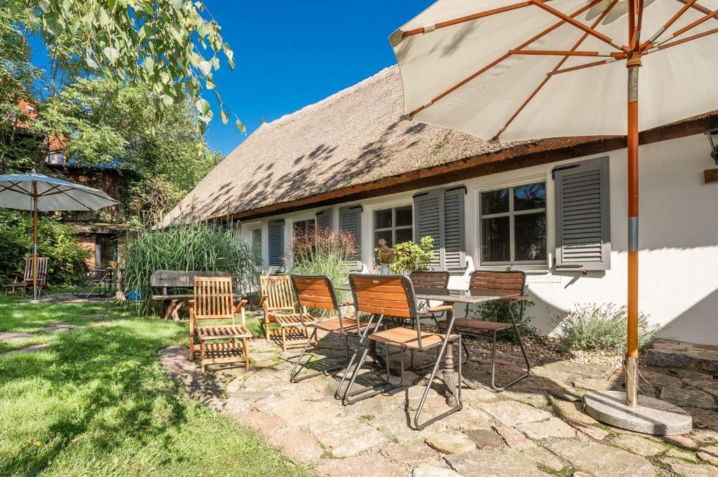a table and chairs with an umbrella in front of a house at Große Use in Benz