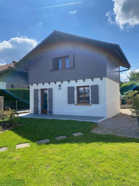 une maison avec une pelouse verte devant elle dans l'établissement Chalet de pécheur entièrement rénové, proche du Lac Léman, à Anthy
