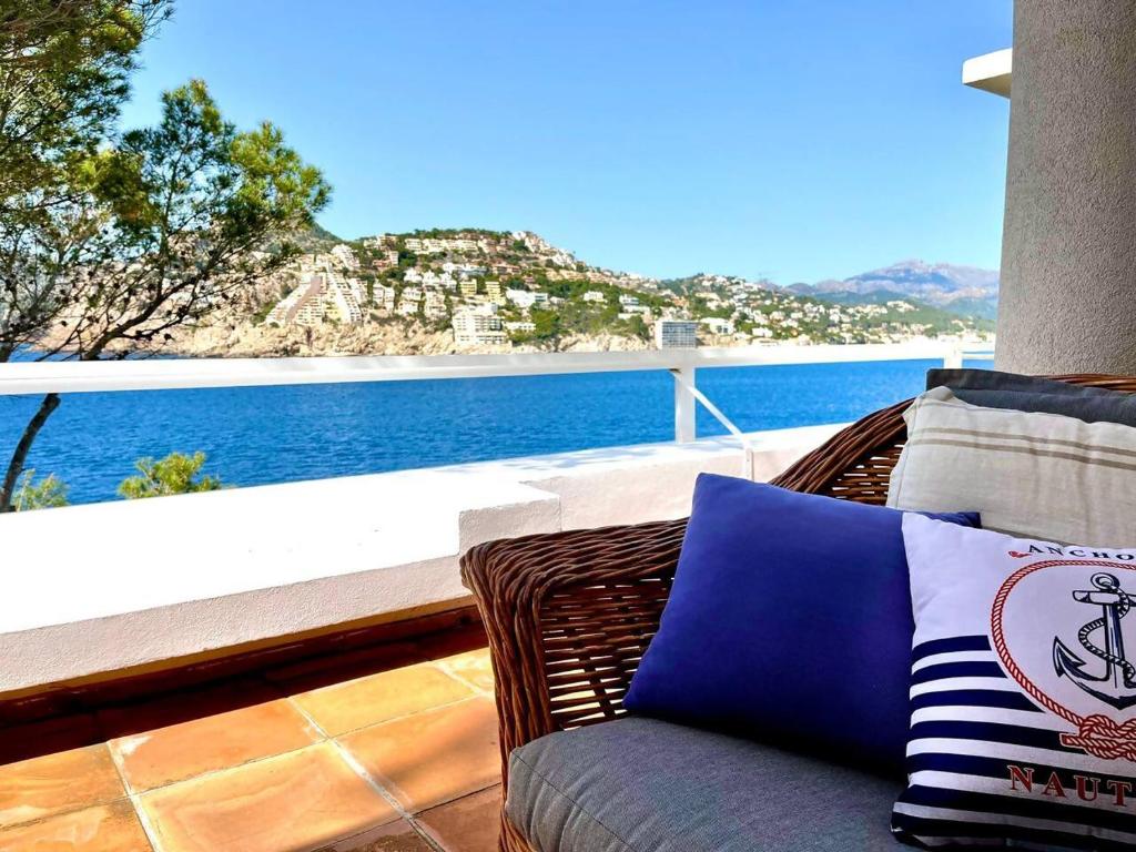 a wicker chair sitting on a balcony overlooking the water at Villa Vistas Dragonera by Mallorca Infinity in Andratx