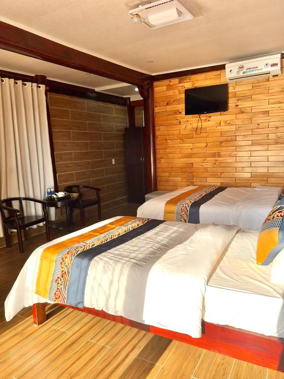 two beds in a room with a tv on the wall at Mộc Lan resort in Phú Quốc