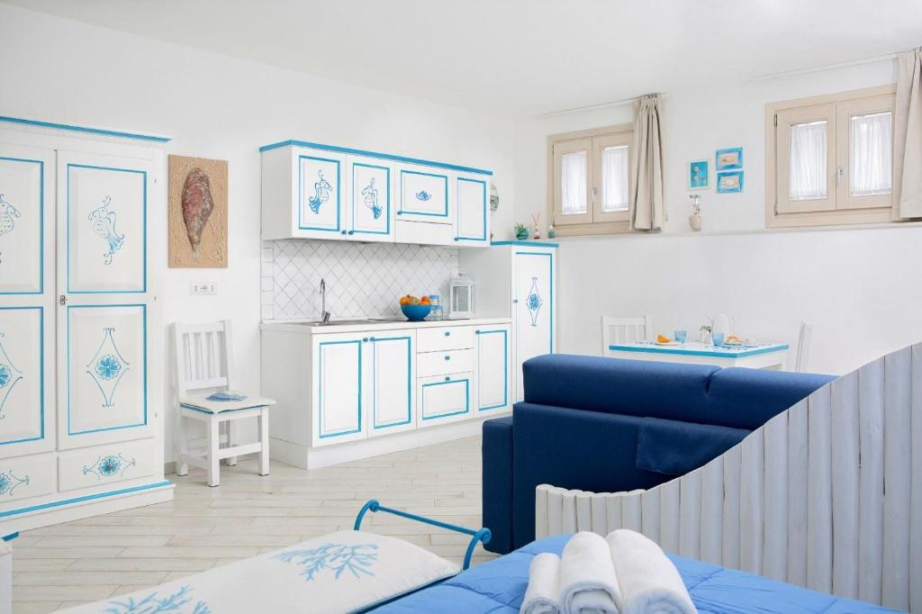 a living room with a blue couch and a kitchen at Monolocale Iride in Santa Teresa Gallura