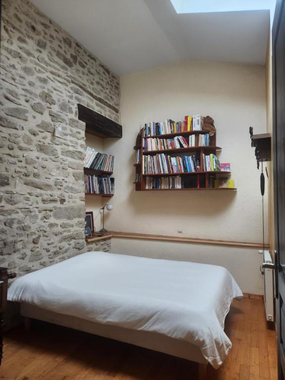 une chambre avec un lit et un mur de briques dans l'établissement la ferme du Planeau, à Montchenu