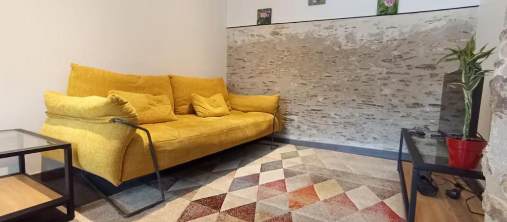 un salon avec un canapé jaune et une table dans l'établissement Le Faubourg Gourdon, à Beaupréau