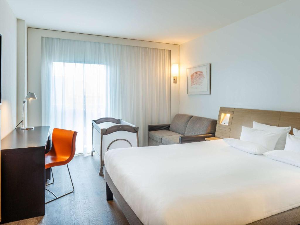 a hotel room with a bed and a couch and a desk at Novotel Barcelona City in Barcelona