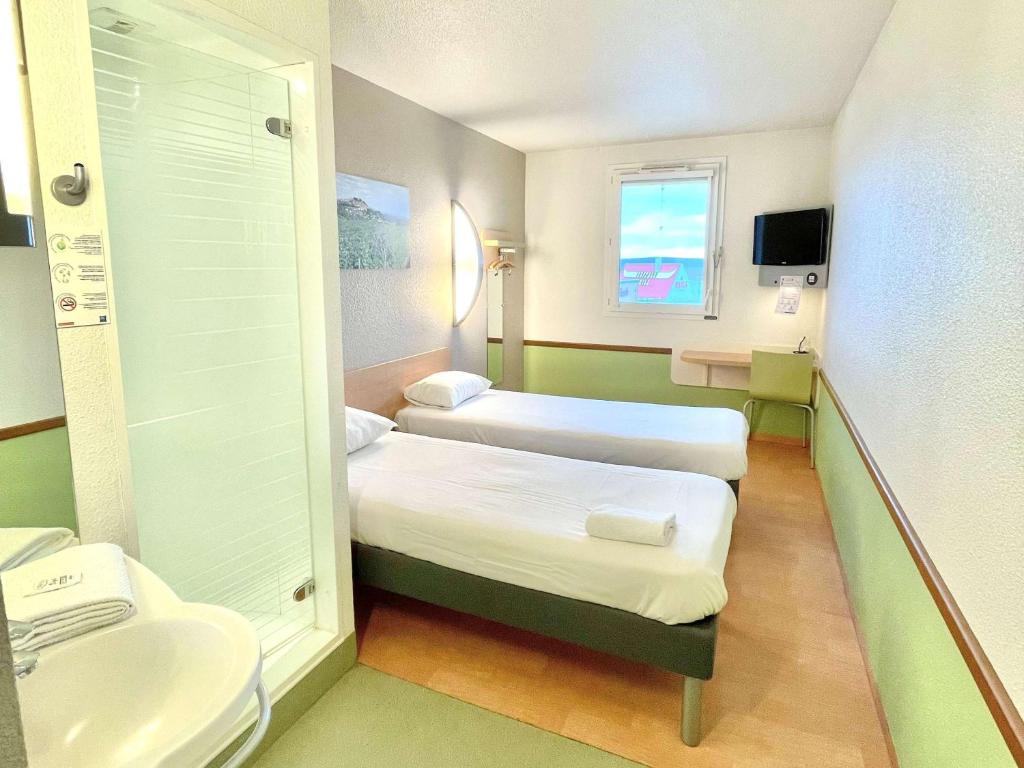a small room with two beds and a sink at Hotel Ibis Budget Cosne Sur Loire in Cosne-Cours-sur-Loire