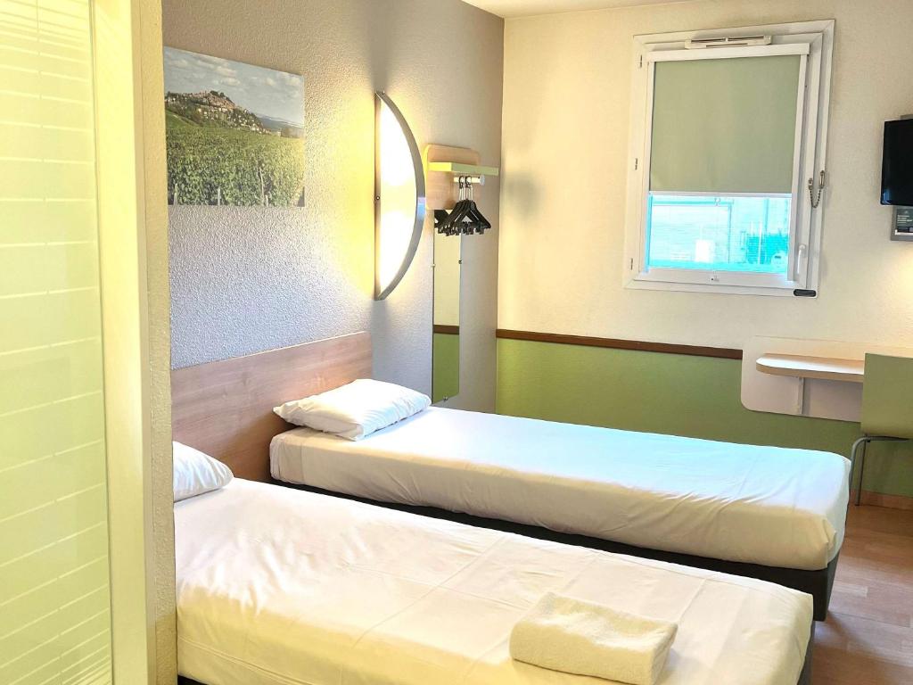 a hotel room with two beds and a mirror at Hotel Ibis Budget Cosne Sur Loire in Cosne-Cours-sur-Loire