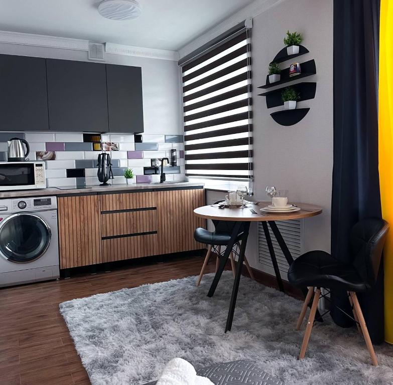 cocina con mesa, fregadero y microondas en Comfort Spot, en Shakhtīnsk