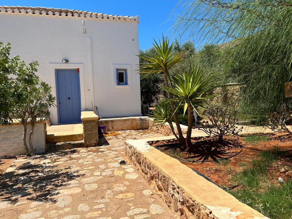 a small white house with a blue door in a yard at Simos suites in Elafonisos