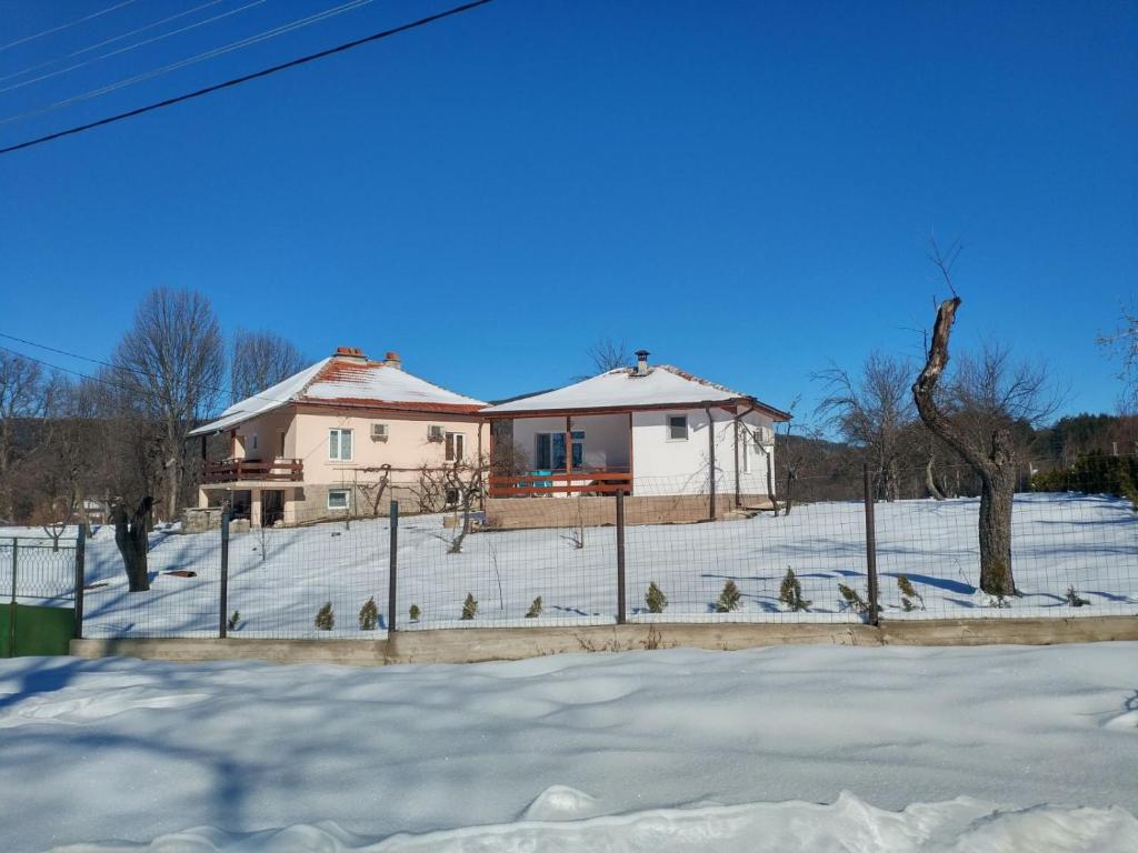 a house in the snow with birds in front of it at Осоговска Бистрица in Gŭrlyano