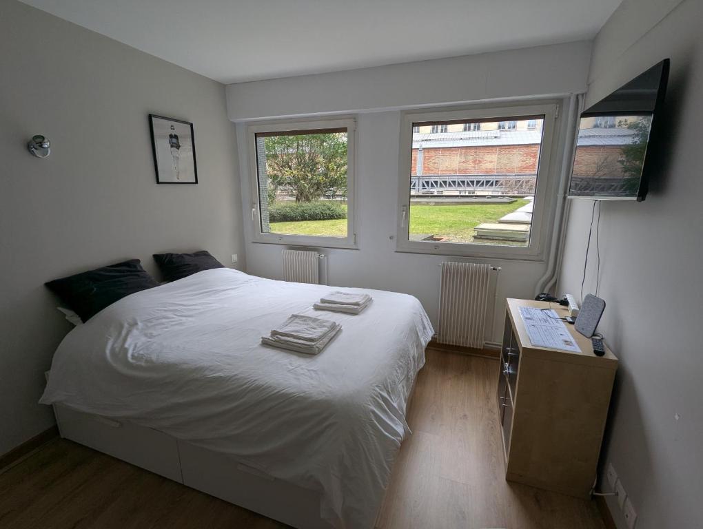 - une chambre avec un lit blanc et 2 fenêtres dans l'établissement Studio équipé proche Tour Eiffel, à Paris