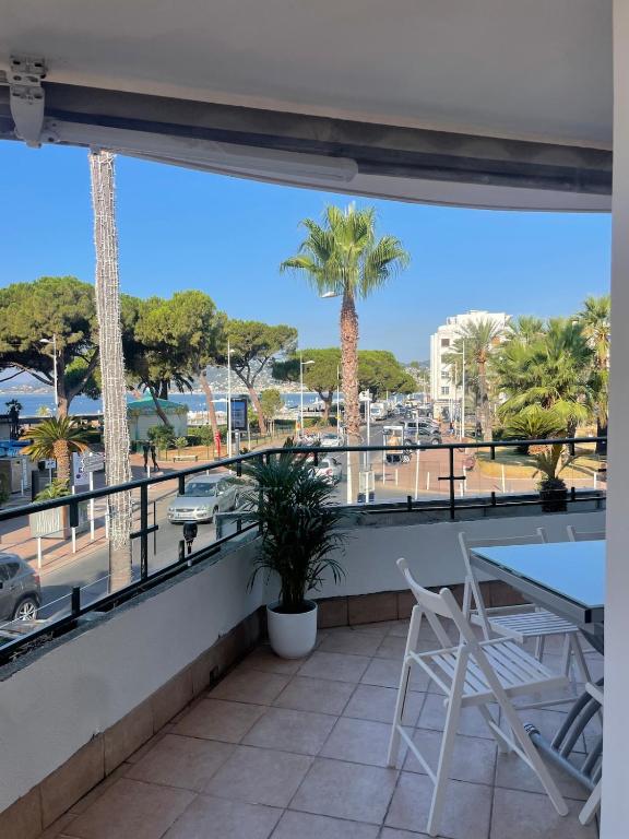 un balcon avec une table, des chaises et des palmiers dans l'établissement Face à la mer et à 2 pas des plages Juan les Pins 'Tout à pied', à Antibes