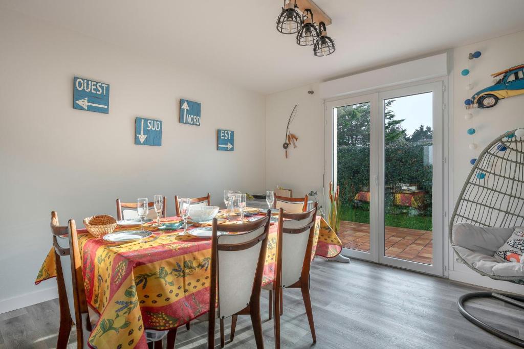 d'une salle à manger avec une table, des chaises et une porte en verre. dans l'établissement Maison a 950m de la mer avec jardin pour 6, au Croisic