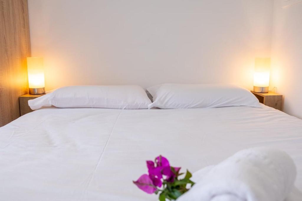 a white bed with a purple flower on it at GuestReady - Tranquil Retreat in Nature's Embrace in São Vicente