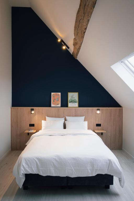 a bedroom with a large bed with a black wall at La Ferme de la Gloriette - Gîte & Spa in Émines
