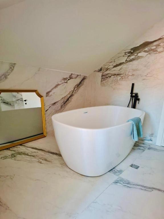 a white bath tub in a bathroom with a mirror at Tudisi Loft Room in Dubrovnik