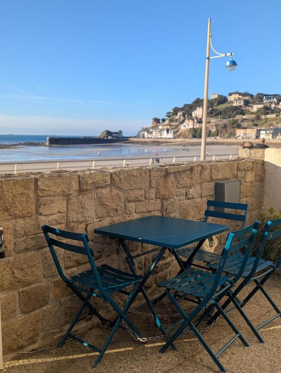 une table et deux chaises assises à côté d'un mur dans l'établissement Maison Ty Bihan face à la plage de Pleneuf, à Pléneuf-Val-André