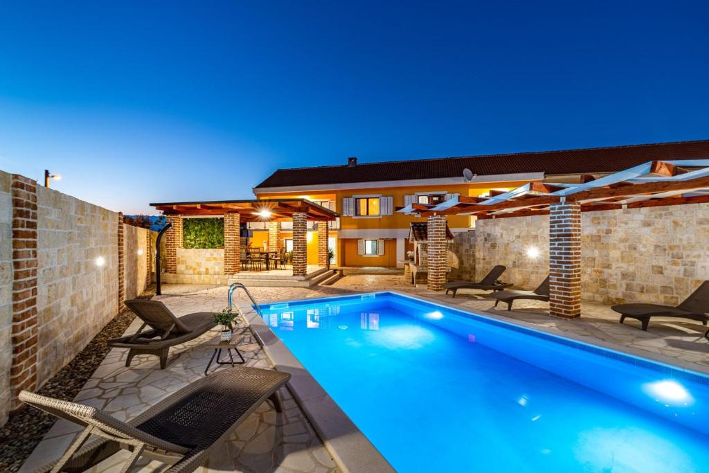 una piscina con sedie e una casa di Villa Mendula ZadarVillas a Pridraga