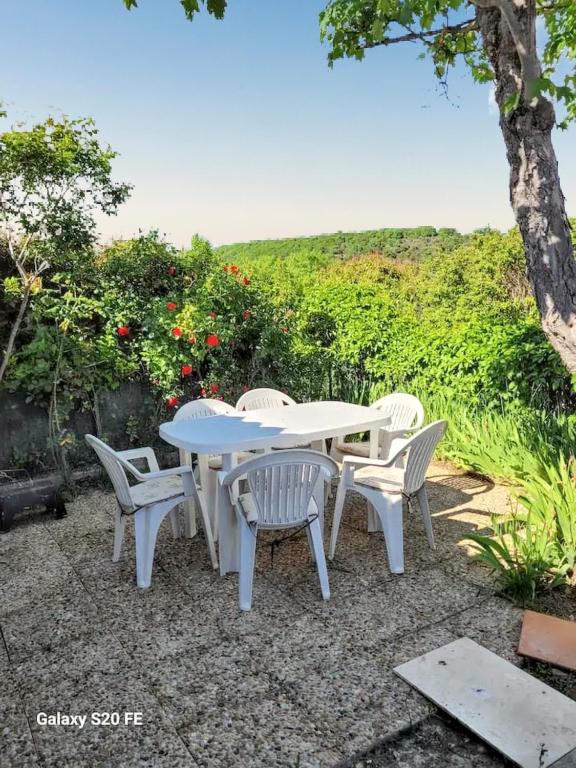 une table et des chaises blanches sur une terrasse en gravier dans l'établissement Maison charmante à Saint-Michel-l'Observatoire avec jardin, à Saint-Michel-lʼObservatoire