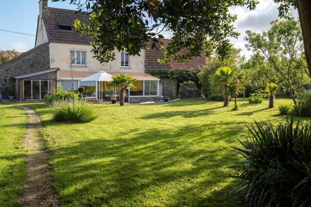 une maison avec une grande cour ornée de palmiers dans l'établissement La Ferme Du Tôt, à Barneville-Carteret