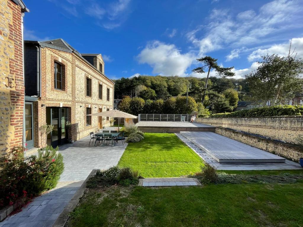 un jardin avec une terrasse et une maison dans l'établissement Maison familiale avec piscine Les Petites Dalles, à Sassetot-le-Mauconduit