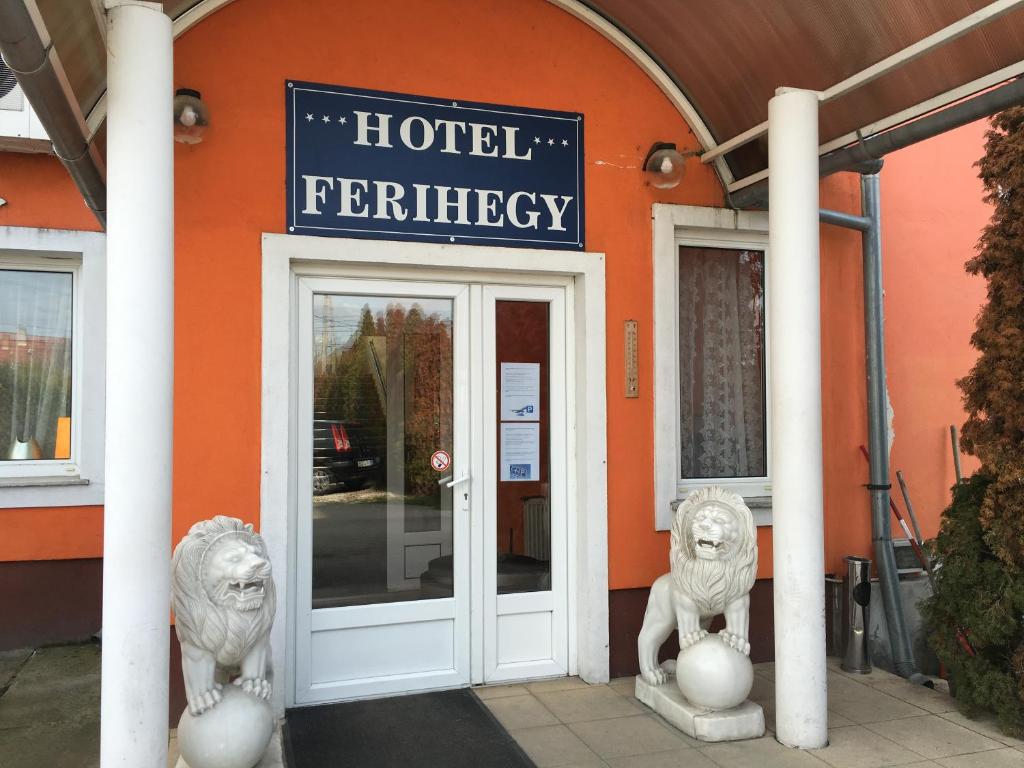 a hotel entrance with two lions in front of a building at Hotel Ferihegy in Vecsés