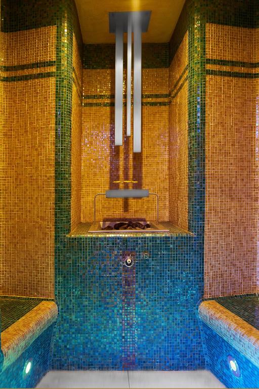 a bathroom with a tub with blue tiles at Retro Riverside Wellness Resort in Karlovy Vary