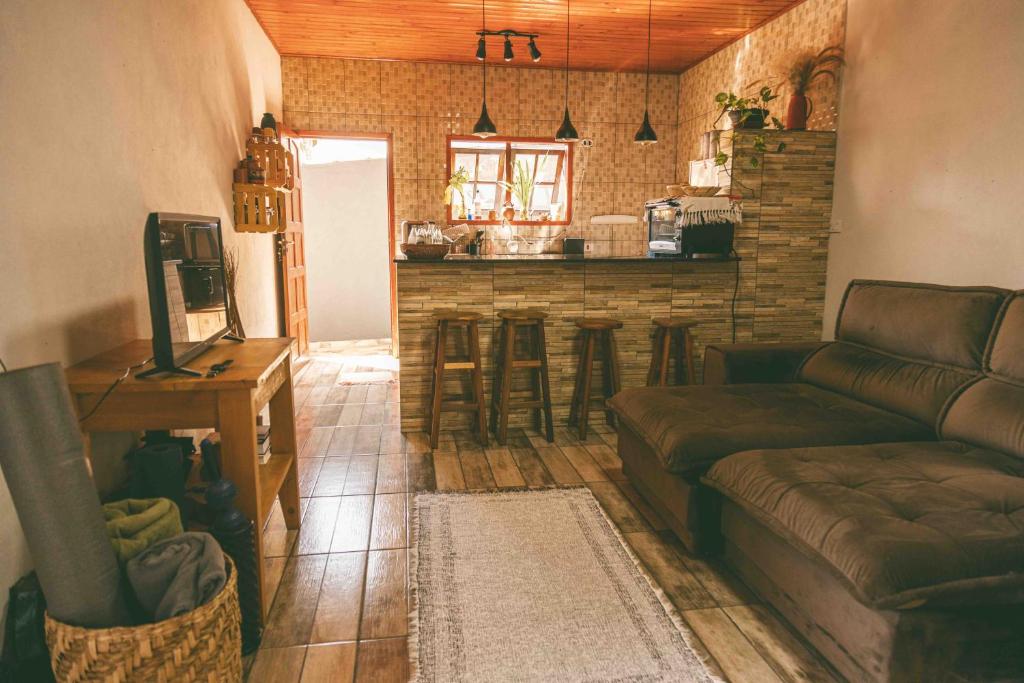 Una sala de estar con un sofá y un bar. en Casinha Pedra do Baú, en São Bento do Sapucaí