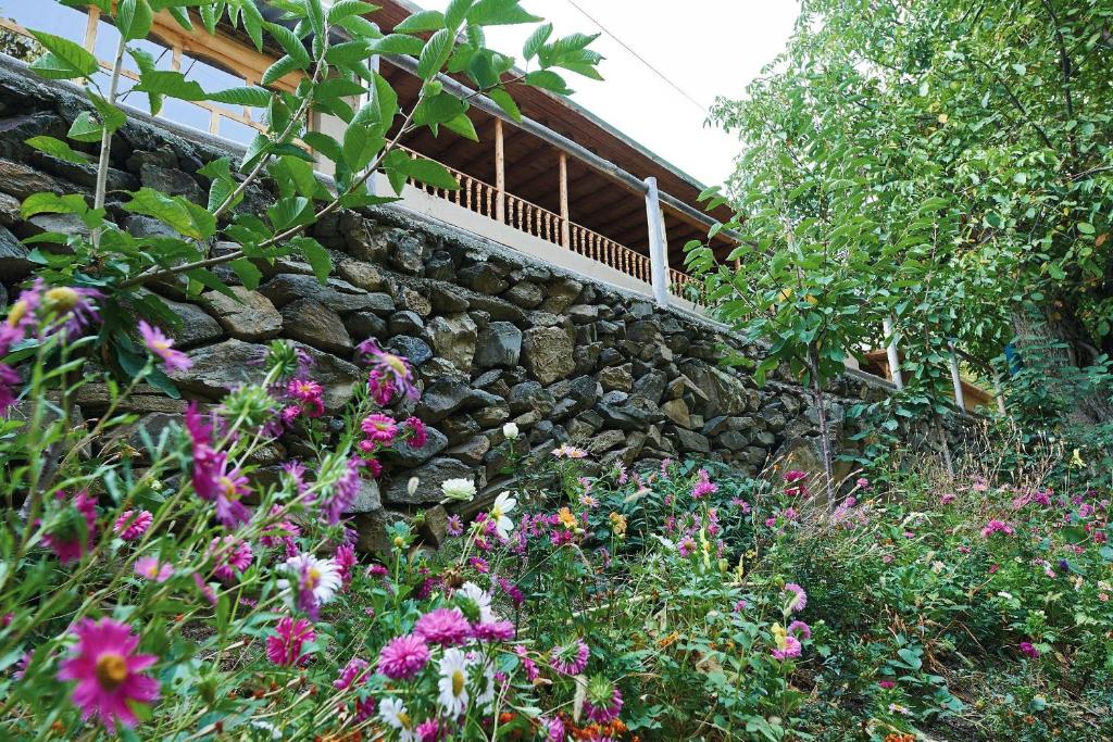 a garden with a stone wall and flowers at Ulugbeks guesthouse in Yukary-Ukhum