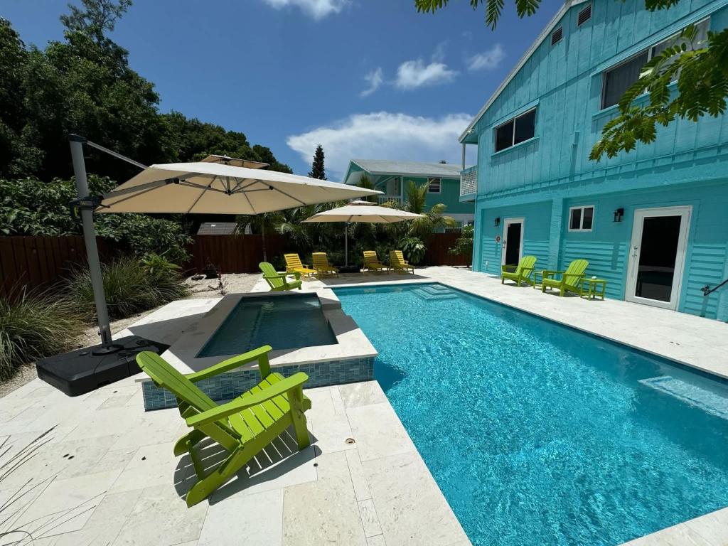 una piscina con sedie verdi e ombrellone di Key Largo Home with Spa and Pool a Key Largo