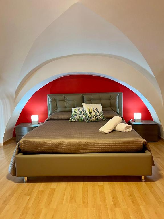 sypialnia z dużym łóżkiem i czerwoną ścianą w obiekcie Aitnè - Holiday Apartments w Katanii