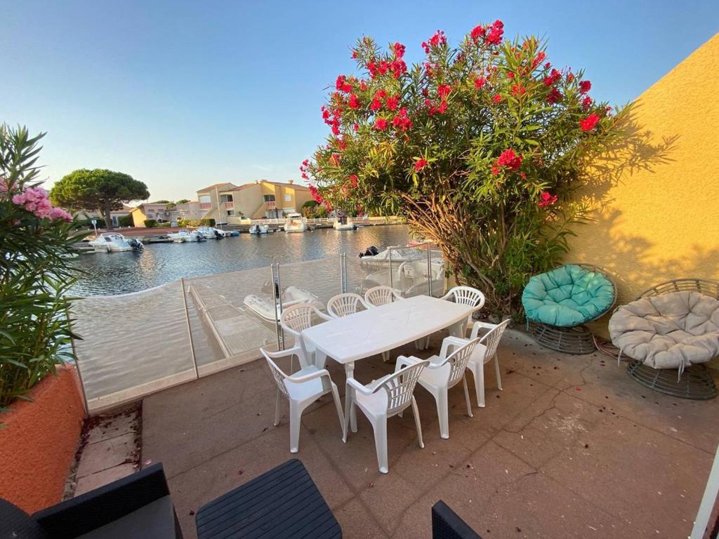 a patio with a table and chairs next to a body of water at Marina 5P avec piscine et terrasses, 4 chambres, clim, parking, proche plage et commerces, Port Barcarès - FR-1-81-554 in Le Barcarès