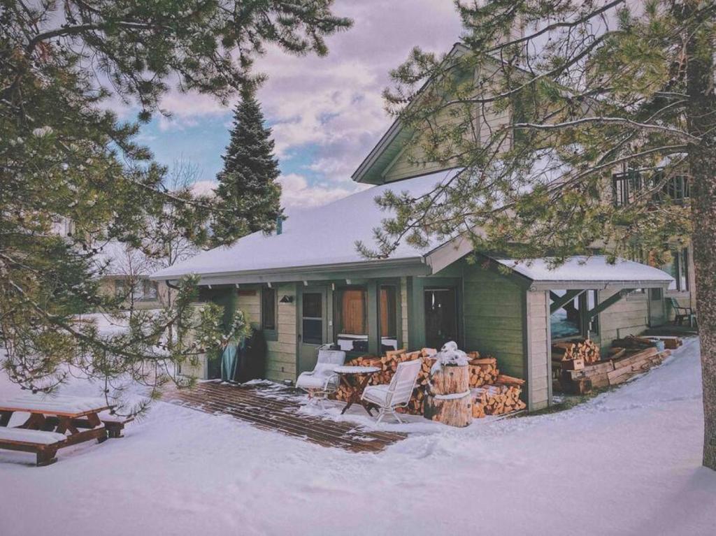 a green house in the snow with a porch at Big Sky Bungalow in Big Sky