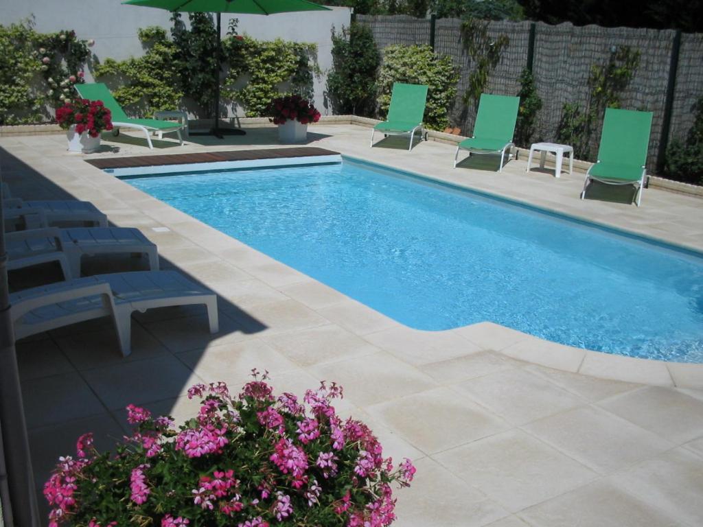 - une piscine bordée de chaises vertes et de fleurs dans l'établissement aucun, à Saint-Rémy-de-Provence