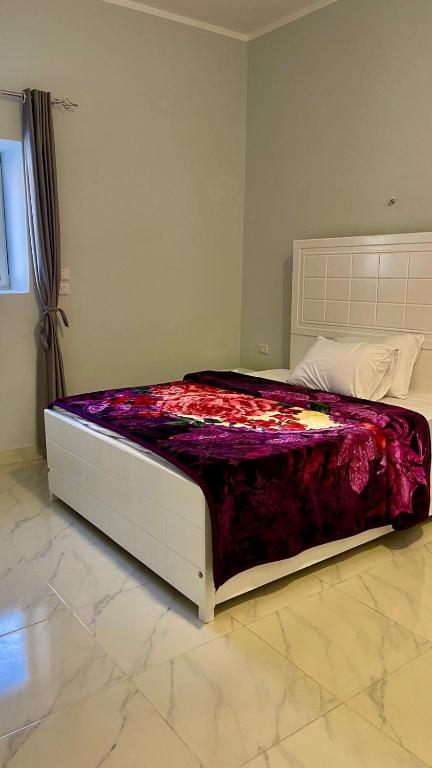 Una cama en un dormitorio con una manta morada. en Alhadi Guest house, en Luxor