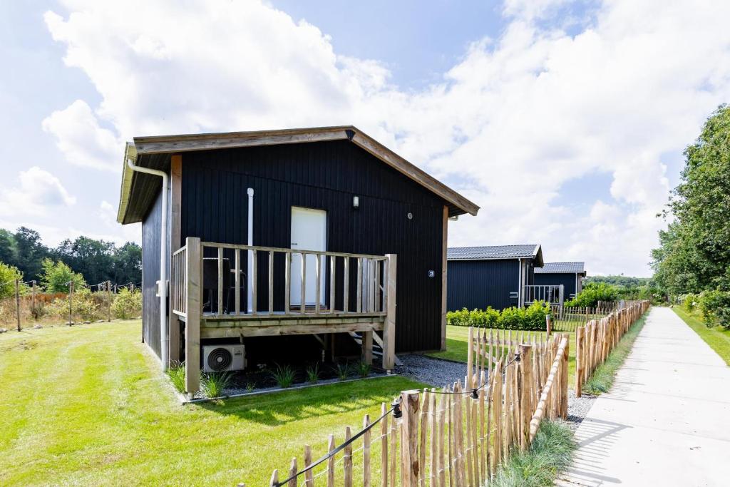 a black house with a deck and a fence at Tiny House XL | 2 persons in Gasselte