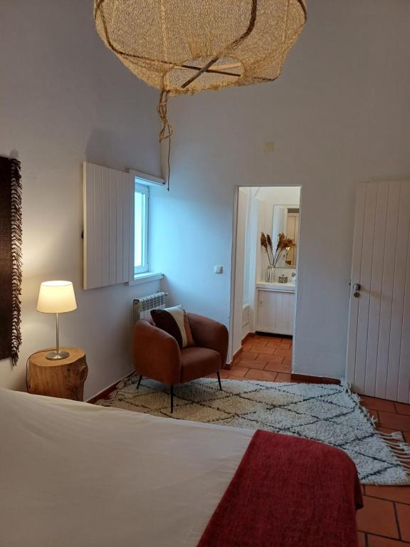 a room with a bed and a chair and a lamp at Comporta House in Comporta