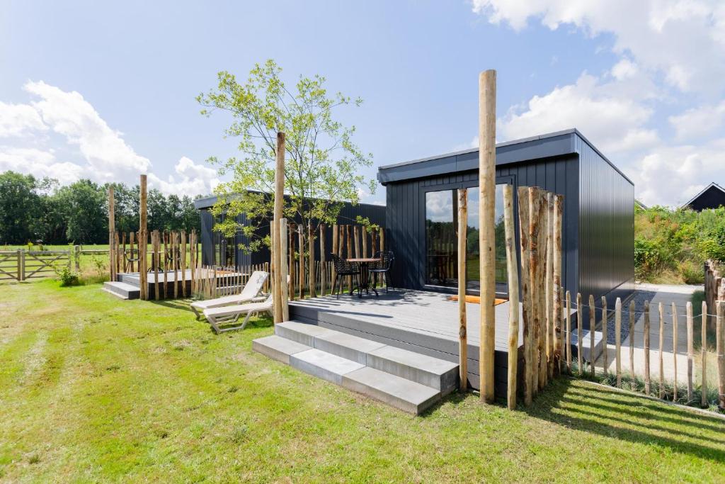 a small black house with a deck and a fence at Tiny House with decking | 2 persons in Gasselte